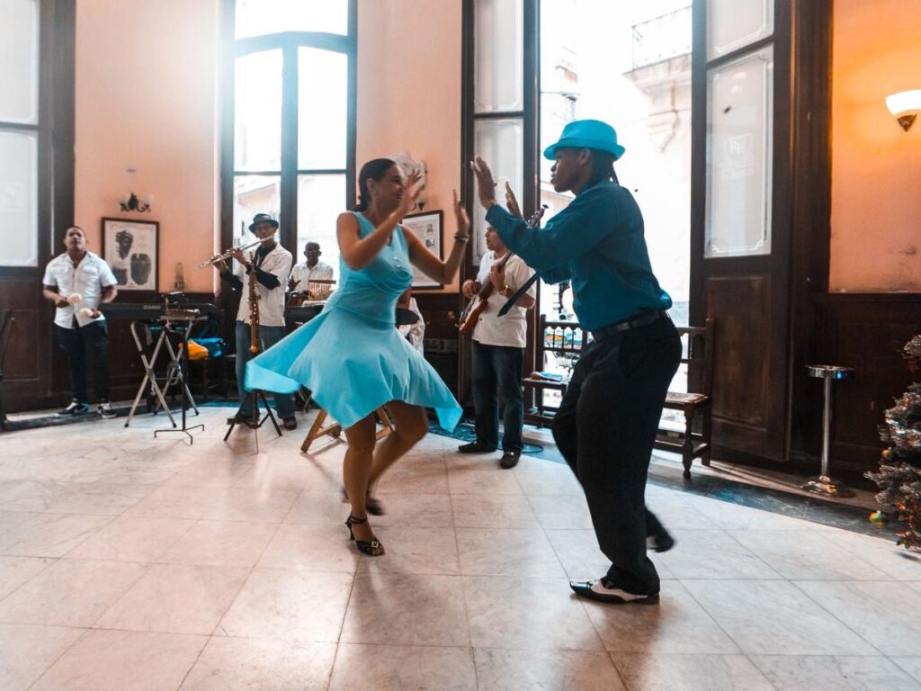 Música dominicana: merengue, bachata y reggaetón en 2026 A lively dance performance capturing joy and rhythm in a bustling café with live musicians.