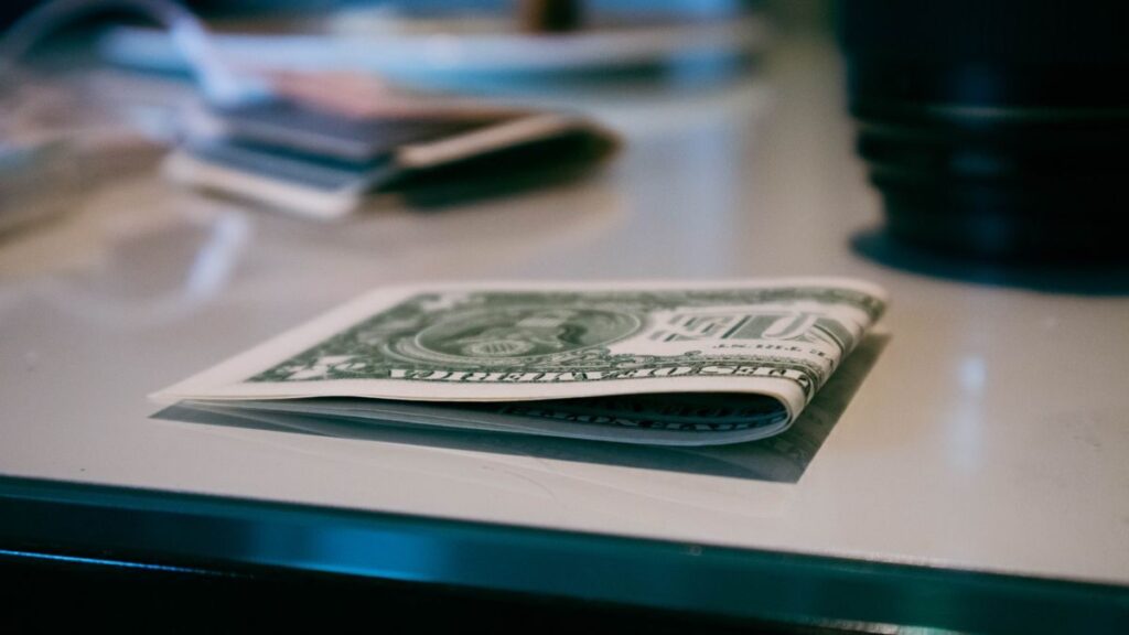 Propinas en el Caribe: guía esencial para turistas Detailed shot of a folded US dollar note on a reflective surface indoors.