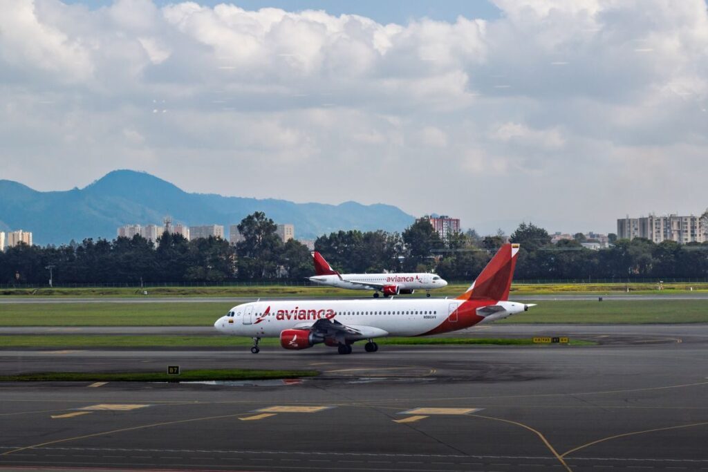 Vuelos desde Bogotá al Caribe: conexiones y aerolíneas Avianca passenger aircraft on the runway at Bogotá, Colombia airport with city and mountains in background.