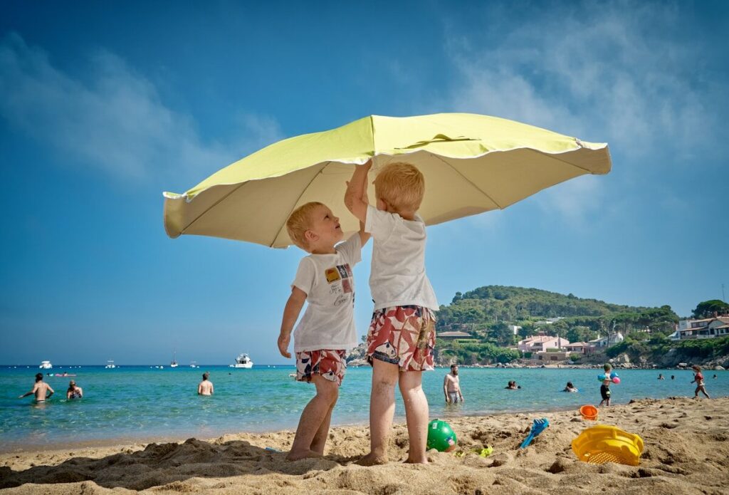 Mejores destinos en el Caribe para viajar con niños two children playing under umbrella on seashore